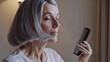 © flashmovie - Senior woman combing her gray hair in the morning, enjoying her beauty routine while embracing natural aging and prioritizing self-care as part of her daily wellness practices