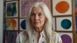 © ULTRA STOCK'S - Female painter from the baby boomer generation with long, white hair posing in front of her paintings