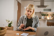© Miljan Živković - Young woman hold and drink medical drug at kitchen at home