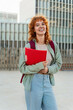 © EFStock - University student portrait of red-haired girl looking at the camera with a folder and backpack smiling