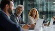 © liliyabatyrova - Colleagues engage in a focused discussion about business strategy in a contemporary office environment, surrounded by sleek glass walls and technology