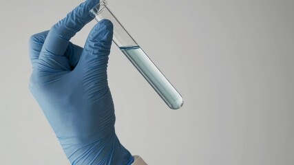 Poster - Laboratory technician wearing blue gloves holds a test tube containing light blue liquid, conducting pharmaceutical research on a white background