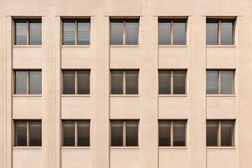 Aufkleber - Facade of a stone building with a symmetrical pattern of dark windows. Light colored stone and geometric design. Architectural detail.
