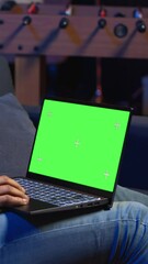 Poster - vertical video african american young guy using device with green screen from his sofa, enjoys the c
