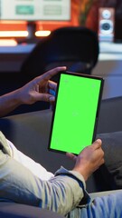 Poster - vertical video black remote worker looking at green screen on his device at home, relaxing in the li