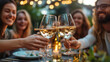 © jainul - group of friends toasting with white wine on an outdoor table at the dining area in their garden, laughing and enjoying each other's company during the summer time