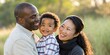 © RisanRisan - Loving black dad and asian mom with laughing kid surrounded by greenery