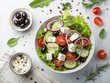 © Amina - A fresh vegetable salad with lettuce, cucumber, cherry tomatoes, red onion, black olives, and feta cheese is served in a white bowl