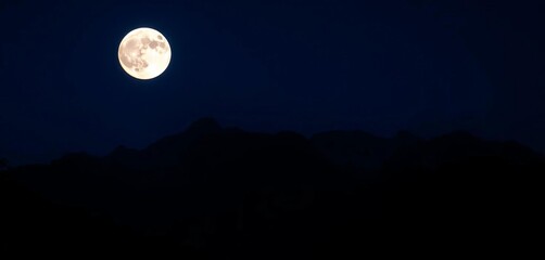 Wall Mural - Austrian Alps silhouetted against a dark blue night sky, a brilliant full moon hanging high,  illuminated, wilderness