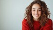 ©  Shomixer - A radiant woman with curly hair smiles brightly in a cozy red sweater, embodying warmth and comfort while presenting a modern and stylish appearance in a clean aesthetic.
