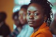 © Baba Images - Young black businesswoman in focus during a office meeting with other employees