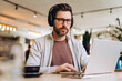 © Maria Vitkovska - Focused businessman wearing headphones working on laptop in cafe