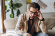 © Maria Vitkovska - Stressed man suffering from headache touching his forehead at home