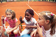 © Marko Geber - Group of young girls with tennis rackets on clay court smiling