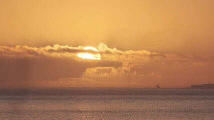 Wall Mural - warm golden sunlight bathing calm ocean waters, casting soft orange hues across cloud formations whi