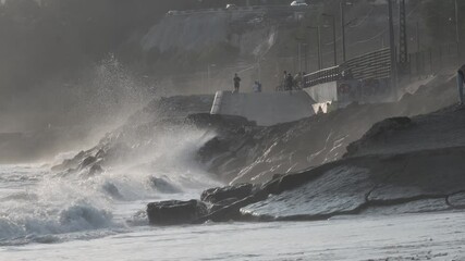 Wall Mural - powerful ocean waves crashing against rugged rocky coastline, generating white foam and misty spray 