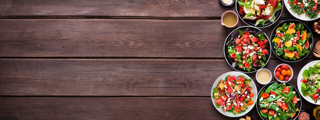 Leinwandbilder - Assortment of delicious fresh salads. Top view side border on a dark wood banner background. Summer food concept.