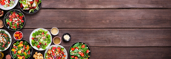 Leinwandbilder - Variety of delicious fresh salads. Above view corner border on a dark wood banner background. Summer food concept.