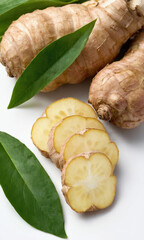 Poster - Freshly sliced ginger with green leaves on a white surface, perfect for cooking and culinary use