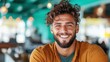 ©  Shomixer - A happy young man with curly hair wearing a mustard shirt, radiating positivity and charm against a vibrant turquoise café backdrop, embodying youthful energy and style.
