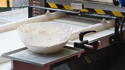 Poster - A bowl of flour is on a counter next to a machine. The bowl is almost empty and the machine is in the background. Bread bakery concept background.
