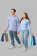 © Pixel-Shot - Beautiful young couple with shopping bags on grey background