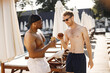 © prostooleh - Two male friends in a swimwears relaxing with a cocktails near swimming pool