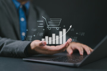 Poster - Sale growth concept. Businessman using laptop with graph of increase in sales volume with shopping cart on virtual screen for ecommerce growth.