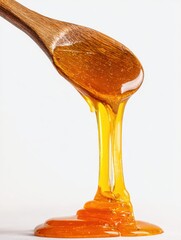 Poster - Golden honey dripping from a wooden spoon against a bright white background in studio shot