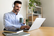 © Daniel - Caucasian man with headphones working at home office. Happy male entrepreneur using laptop.