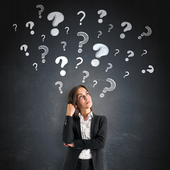 Fototapete - Thoughtful businesswoman standing near black wall with many hand-drawn question marks floating above her head, representing curiosity and problem solving.