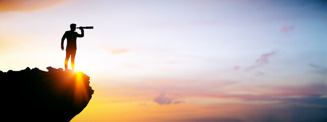 Poster - Businessman silhouette looking through telescope on cliff during sunrise, symbolizing vision, opportunity and success in business strategy concept.