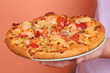 © belrync - Hand holding Hawaiian pizza