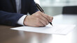 © Soem - A man in a suit signing a document with a pen on a desk.