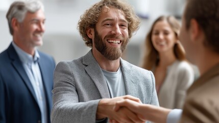 Fototapete - Two business professionals shake hands to conclude a successful meeting, while colleagues look on with positive expressions in a modern office environment
