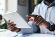 © pressmaster - Closeup of hands of unrecognizable black male businessman sitting in office, using digital tablet