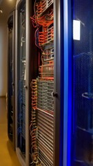 Poster - Row of data servers with blinking lights and wires in a computer room, network communication and high-speed internet hardware.