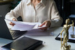© pressmaster - Unrecognizable female lawyer working with documents at desk with laptop, notebook and bronze figure on it
