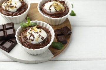 Wall Mural - tasty pudding with whipped cream in bowls and pieces of chocolate on white wooden table, closeup. sp