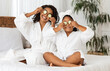 © Prostock-studio - Playful black mother and little daughter in bathrobes applying cucumber pieces to eyes, having fun together after bathroom, cute girl and mom sitting on bed, enjoying home beauty spa day, copy space