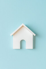 Poster - Minimalist white house icon on light blue background. Flat lay style, perfect for real estate or home concept. Clean and simple design.
