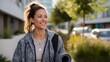 © Rodrigo - A cheerful woman is seen smiling outdoors while carrying a yoga mat, suggesting a healthy and active lifestyle in an urban setting.