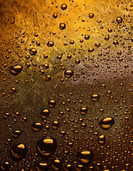 Leinwandbilder - Golden drops of water on a textured surface create an abstract background.