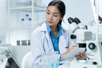 Wall Mural - asian researcher using a microscope in the clinical lab.female researcher working in the clinical la