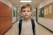 © Jafree - Young caucasian boy with backpack standing in school corridor. concept of childhood education, back-to-school, academic environment