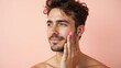 © PremiumPhoto - Sensitive Skin. Young man with curly hair applying moisturizer skincar