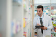 © ultramansk - man pharmacist checks and arranges medicines on pharmacy shelves, emphasizing precision and responsibility in healthcare services. The scene highlights the daily operations in a modern pharmacy.