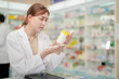 © ultramansk - A woman pharmacist inspects a medication bottle, ensuring accuracy in prescription filling. pharmacists in patient safety and careful medication handling. daily operations in a modern pharmacy.