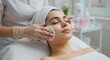 © SerPak - Young caucasian female receiving facial treatment at spa with skincare products.