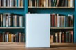 © Anna - Blank book cover on wood table with blurred shelves